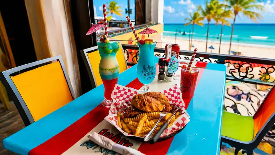 Food and colorful tropical drinks on a table overlooking Fort Lauderdale Beach.