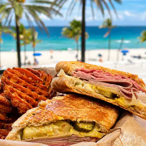 Pressed Cuban sandwich cut in half and served with crinkle-cut fries